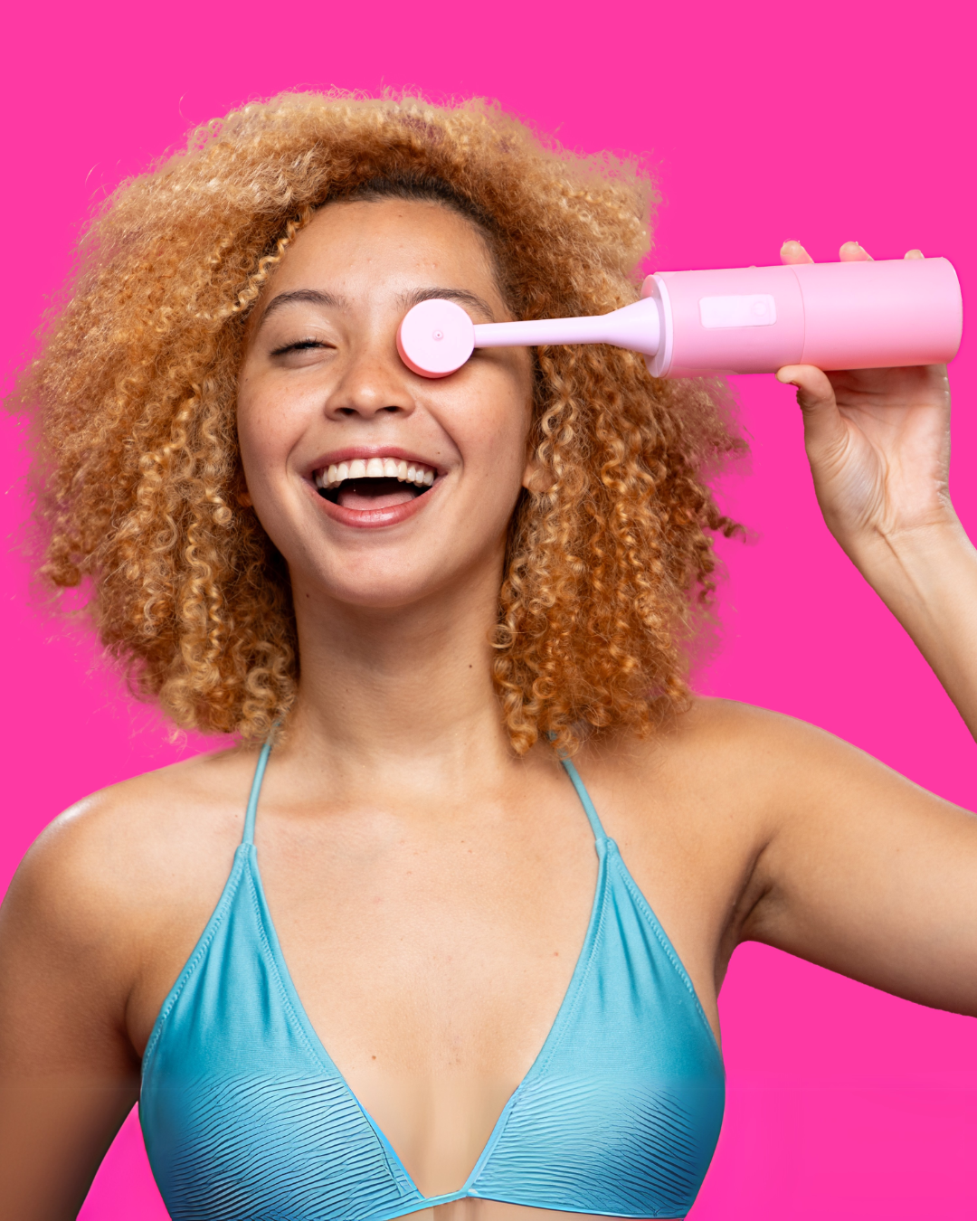 Woman holding a pink electronic portable bidet against a bright pink background