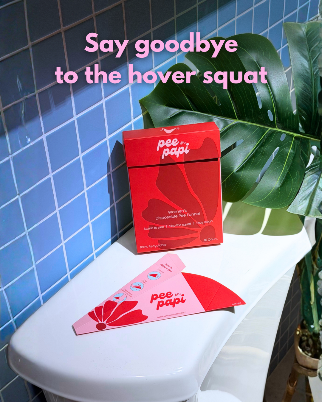 A red box and pink triangular product packet labeled 'pee papi' sit on a white toilet tank against a blue tiled wall, with a large green plant leaf behind them and pink text reading 'Say goodbye to the hover squat'.